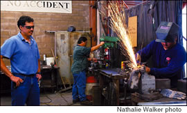 Hard at work at Heide & Cook, Dean Freitas supervises sheet metal worker Jayson Matsuda while, in the background, Alan Ibanes works on the drill press