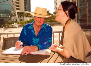 Tracey Saito and Tom Moffatt share a laugh as he autographs her copy of his new book