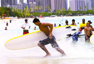 A paddleboard racer dashes out of the water during last summer’s Junior Lifeguard program