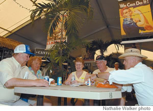 Patrick Brent chats with lunching visitors from Canada and Oregon beneath a poster of the WWII home front heroine Rosie the Riveter