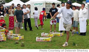 Dan Nakasone, chairman of the Wahiawa Community and Business Association, takes a stab at flipping a pineapple at last year’s Wahiawa Pineapple Festival. Chefs Fred DeAngelo (back left in chef’s coat) and Alan Wong (back right, also in chef’s coat) watch the action