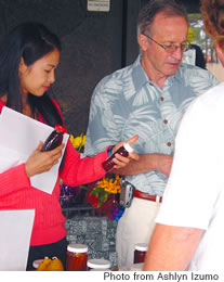 Cecilia Evans tries to choose between flavors of honey at the Koolau Clinic’s Fresh Wednesday market, while Kaiser’s Dr. Vernon Ansdell makes a purchase. The market is open every first and third Wednesday morning.